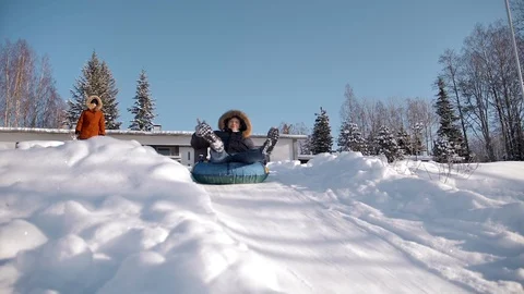 Funny man is rolling down a hill on an inflatable snowtube showing peace gesture Stock Footage 114624545