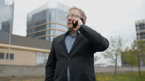 Funny man in suit talking by smartphone and smiling, manager outside office Stock Footage 107908331