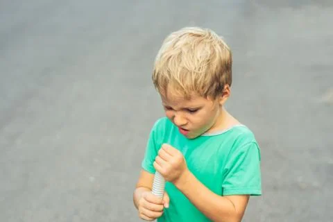 Funny mischievous cute blond boy with freckles face squints, looks into plastic Stock Photos