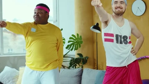 Funny multi-ethnic retro guys doing aerobics exercises in living room. Team of Stock-Footage 132576040