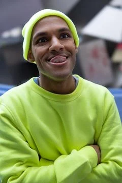 Funny multiracial man looking at camera with tongue out in city Stock Photos