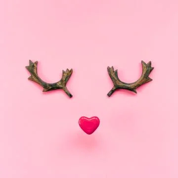 Funny muzzle made of red heart and wooden reindeer horns on a pink background Stock Photos