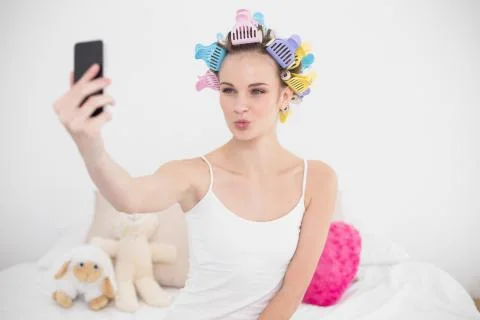 Funny natural brown haired woman in hair curlers taking a picture of herself Stock Photos