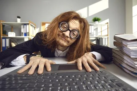 Funny nerd in glasses using laptop and searching for information on the Internet Stock Photos