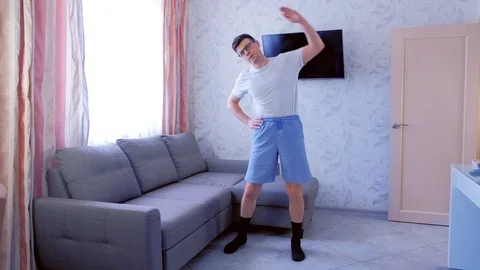Funny nerd man is making tilts to the sides exercise at home in living room Stock Footage 114352872