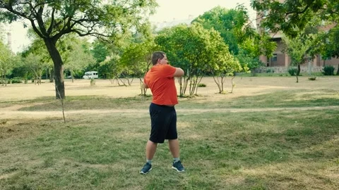 Funny Obese person doing exercises in city park, fat man warming up before Stock Footage 138820102