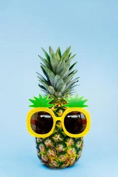 Funny pineapple in a sunglass of pineapple shape on the blue vertical background Stock Photos