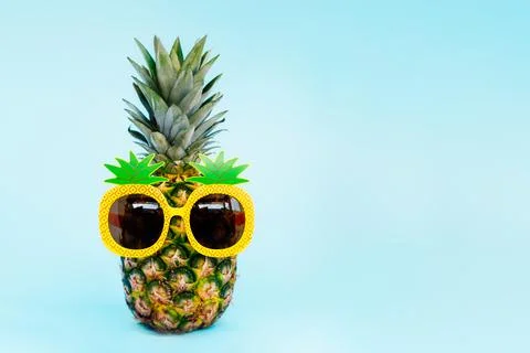 Funny pineapple in a sunglass of pineapple shape on the blue background Stock Photos