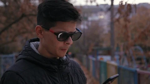 Funny positive young boy in 3D glasses using smartphone outdoors, close up Video stock 98359244