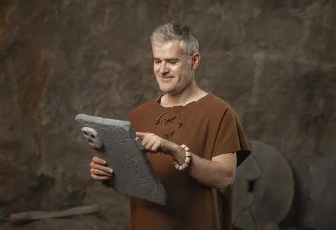 Funny Prehistoric Caveman Using a Primitive Stone Tablet - Ancient Technolo.. Stock Photos