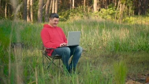 Funny programmer working on laptop in summer forest Stock-Footage 154376029
