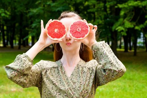 Funny red haired female with grape fruits making silly face. Summer fun conce Stock Photos