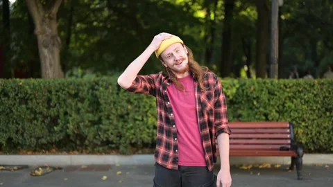 A funny red-haired guy takes off his yellow hat and mannerly shakes his head Vídeo Stock 250629927