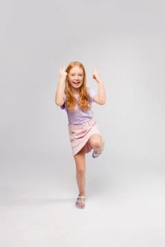 Funny red-haired long-haired girl in daily clothes (skirt, t-shirt) Stock Photos