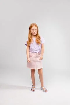 Funny red-haired long-haired girl in daily clothes (skirt, t-shirt) Stock Photos
