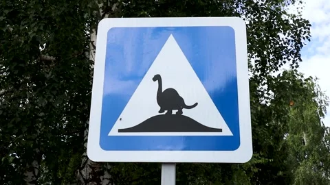 Funny road sign warns drivers of dinosaurs crossing the road Stock Footage 279496252