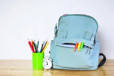 Funny school backpack with markers, colored pencils and an alarm clock on a w Stock Photos