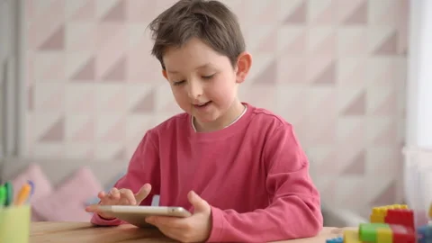 Funny schoolboy boy using tablet computer, sitting at home alone, positive child Stock Footage 153886151