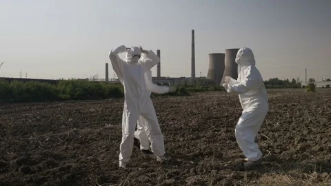 Funny scientists in hazmat suits dancing and fooling around near the location Stock Footage 82178098
