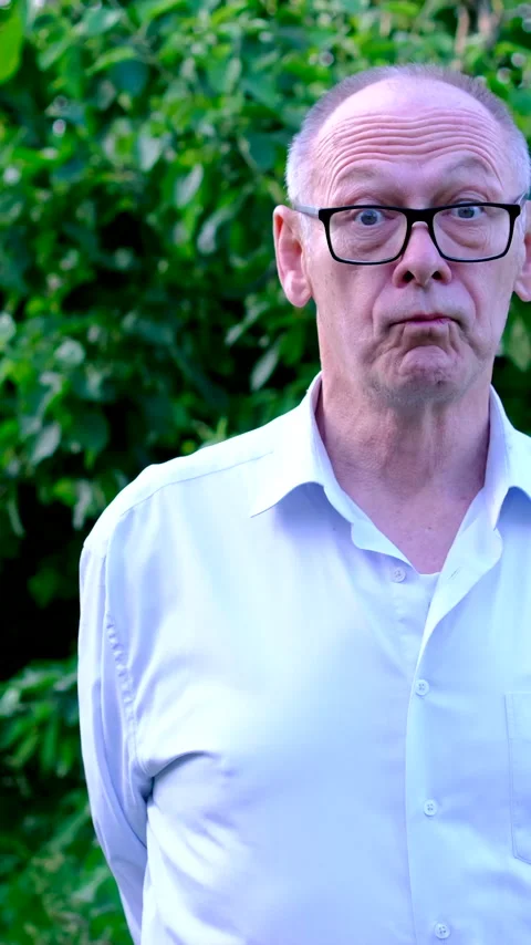 Funny senior man making silly surprised faces with wide eyes and exaggerated Stock Footage 345744167