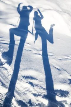 Funny shadows of two people posing on white snow Stock Photos
