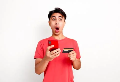 Funny shocked customer looking at camera while holding smartphone and credi.. Stock Photos