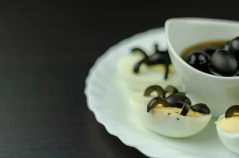 Funny snack with olive spiders on egg halves for halloween party, creative Stock Photos