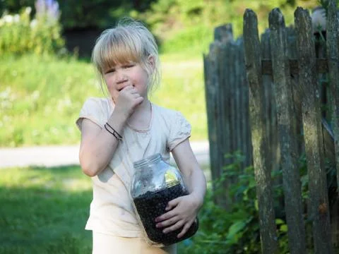 Funny soiled child eats blueberries with pleasure Stock Photos