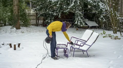 Funny Spring Concept - Melting snow on sun chairs with blow dryer. Stock Footage 46799838
