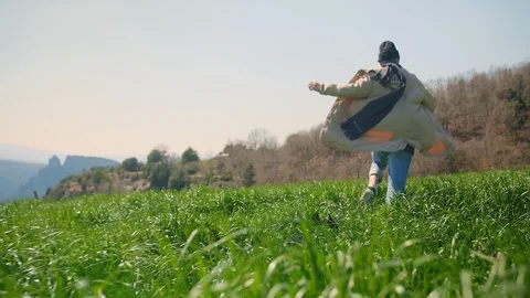 Funny tall man loping trough wild green field with best friend french bulldog at Stock Footage 108439209