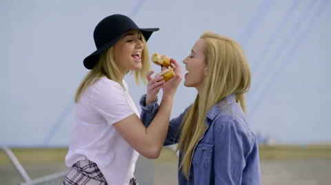 Funny Teens Link Arms And Take A Bite Of Their Donuts (Slow Motion) Stock Footage 62632393