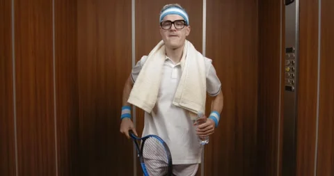 Funny tennis player working out in the elevator Stock Footage 308919499
