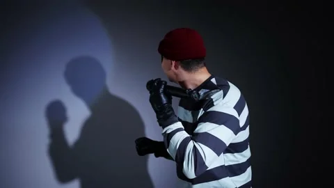 Funny thief with a flashlight in mask and Prison Uniform finger to the lips Stock-Footage 224352299