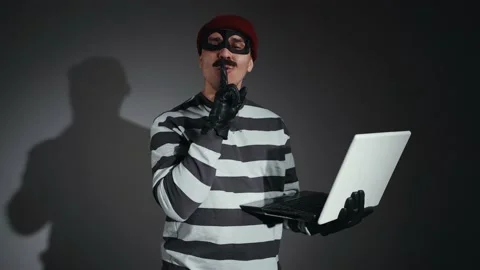 Funny thief in mask and Prison Uniform with a laptop in hand finger to the lips Stock-Footage 222811325