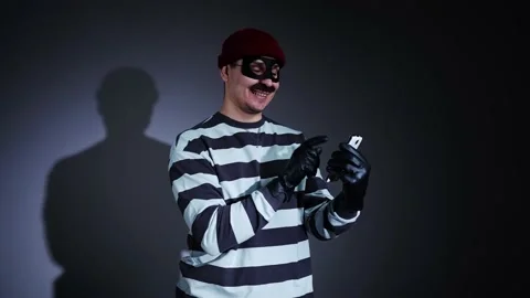 Funny thief in mask and Prison Uniform smartphone in hand Stock-Footage 224529747