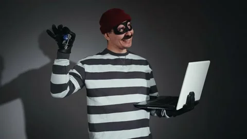 A funny thief in mask and Prison Uniform with a laptop and keys in hand Stock-Footage 224530058