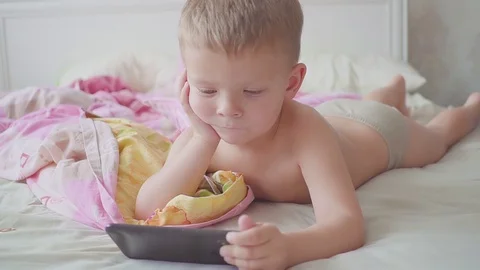 Funny three year old boy in bed is using a smartphone. Video stock 118927972