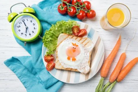 Funny toast with fried egg in a shape of chicken and alarm clock, kids food Stock Photos