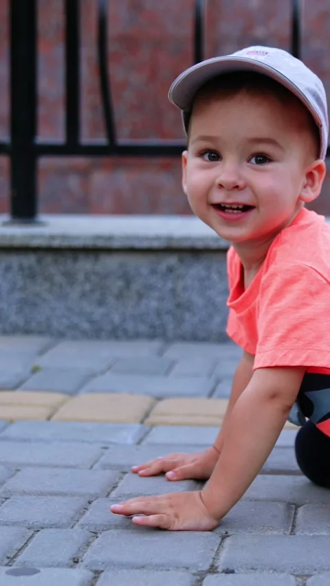 Funny toddler boy crawling by the paved road in the park. Cheerful kid having Stock Footage 330239335