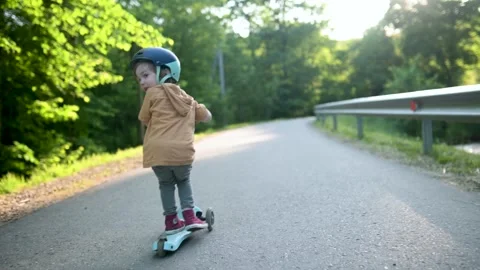 Funny toddler boy riding a scooter outdoors on summer day. Slow motion footage. 스톡 동영상 250201848