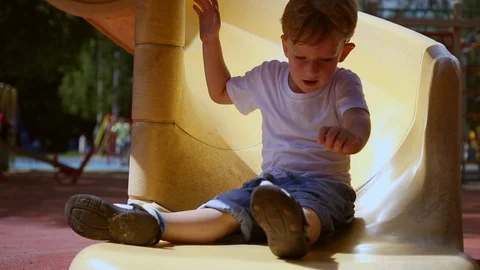 Funny toddler boy slides on a slide Stock Footage 92552876