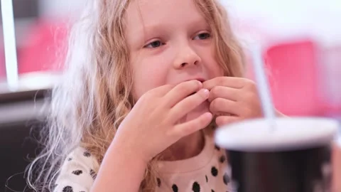 Funny toothless playfull curly smiling Child girl eating French fries potatoes Stock Footage 279550736