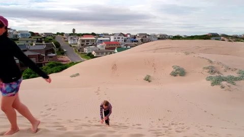 Funny top view of active mom racing daughter laboriously up sandy dune in Stock Footage 335191826