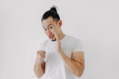 Funny tricky face man telling secret in white t-shirt isolate on white. Stock-Fotos