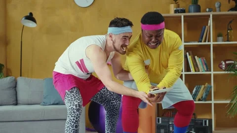 Funny two unfit weird retro stylish young men lifting up weight together. Coach Stock Footage 132578221