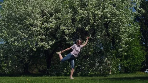 Funny woman in white hat dancing on a green lawn in summer park. Stockbeeldmateriaal 194787203