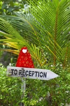 Funny wooden pointer to reception of a tropical hotel with christmas hat, Mal Foto stock