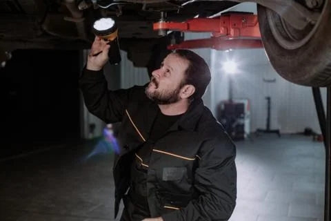 A funny worker analyzes the car from below, being very focused Foto stock