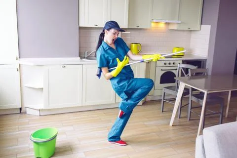 Funny worker dancing in kitchen. She pretends playing on guitar. But girl has Stock Photos