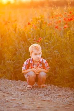 A funny young boy with eye misalignment, smiling and giggling in a sunset-lit Stock Photos